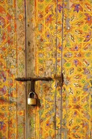 an open door with a lock on it and colorful wall paper behind it in the background