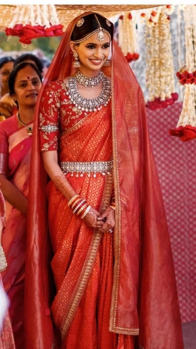 a woman in an orange and red sari is walking down the aisle with other people