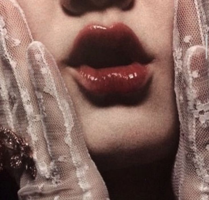 a woman with her hands on her face wearing white gloves and red lipstick is looking at the camera