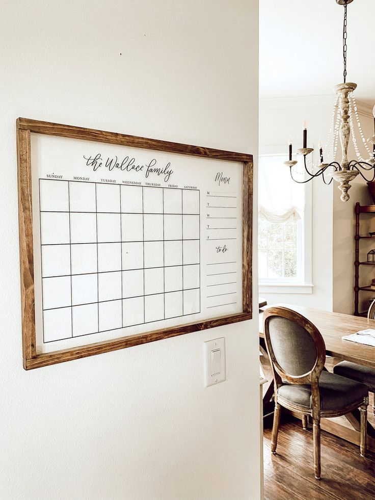 a wooden framed calendar hangs on the wall next to a dining room table