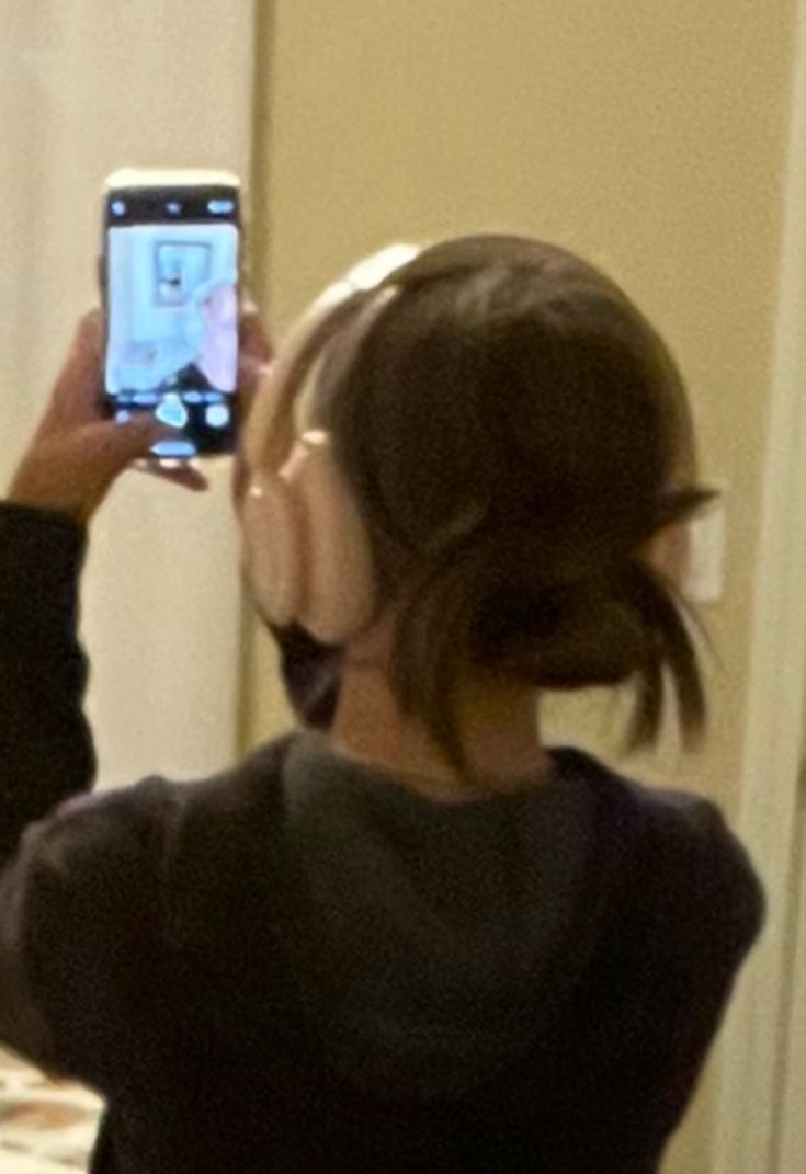 a woman taking a selfie in front of a mirror with her cell phone up to her ear