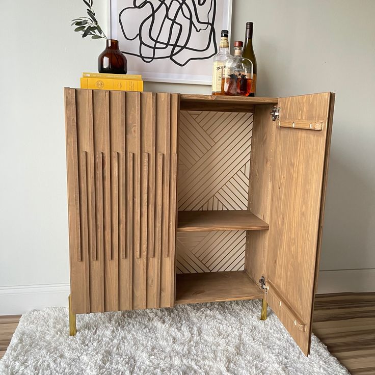 a wooden cabinet sitting on top of a white rug next to a painting and bottles