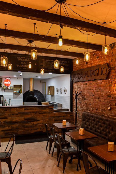 the interior of a restaurant with wooden tables and brown leather chairs, brick walls and exposed ceilings