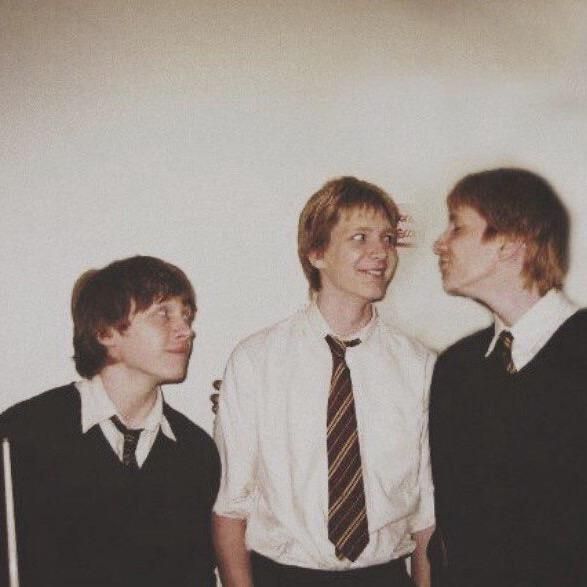 three young men standing next to each other in front of a white wall wearing ties