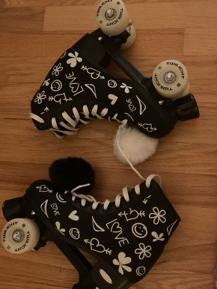 two roller skates with black and white designs on them sitting on a wooden floor