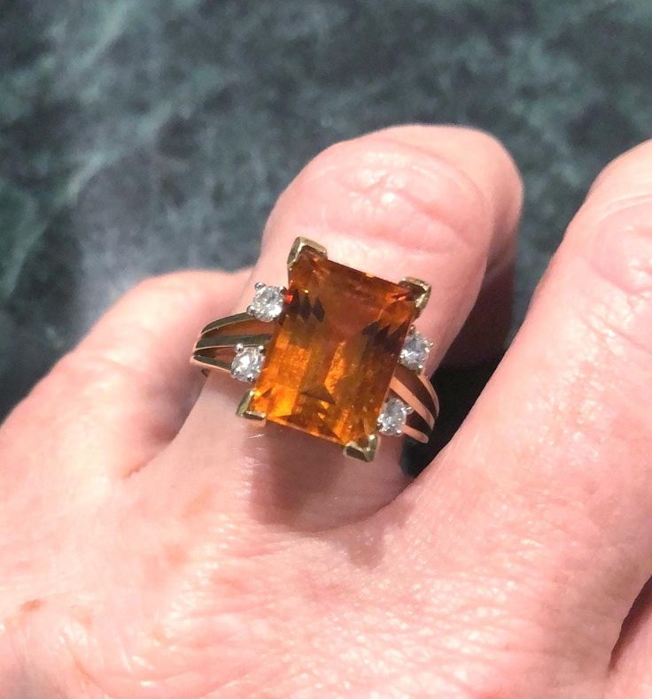 a woman's hand holding an orange and white diamond ring