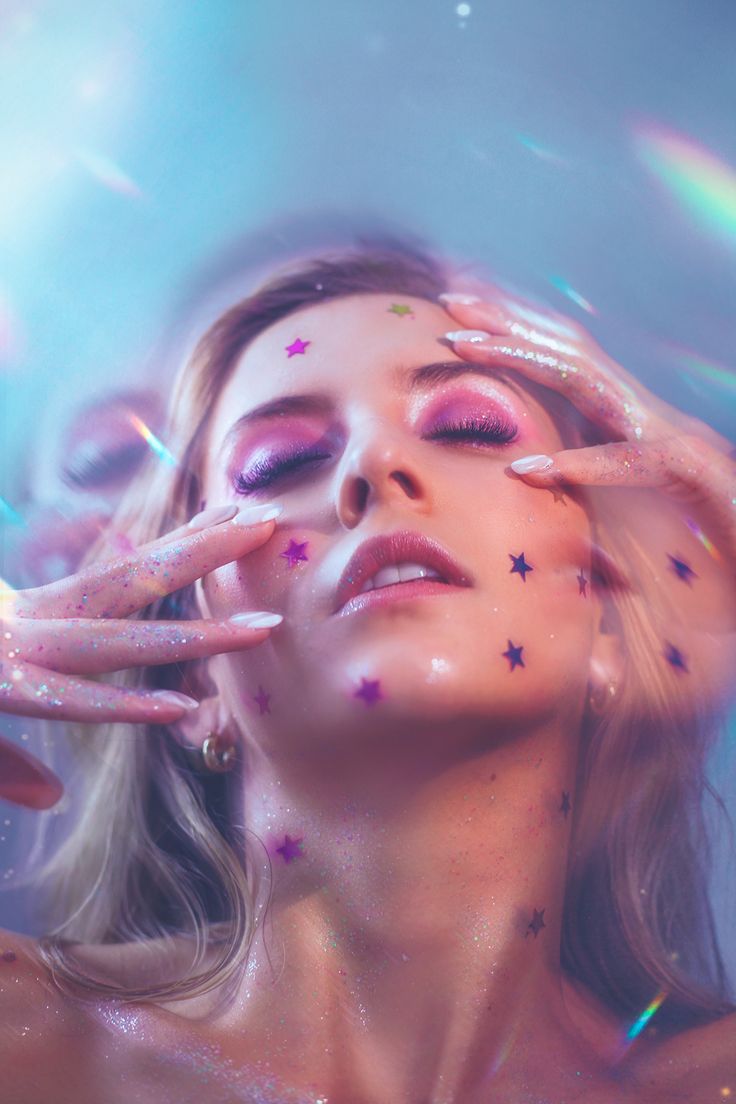 a woman with stars painted on her face and hands in front of her face, surrounded by confetti