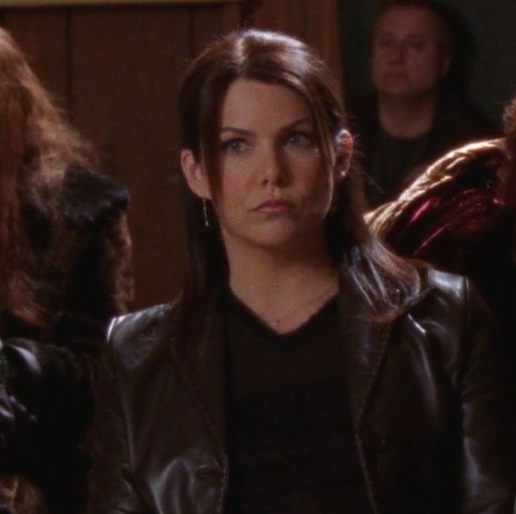 a woman in leather jacket sitting next to other people