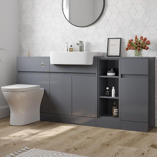 a white toilet sitting next to a gray cabinet in a bathroom under a round mirror