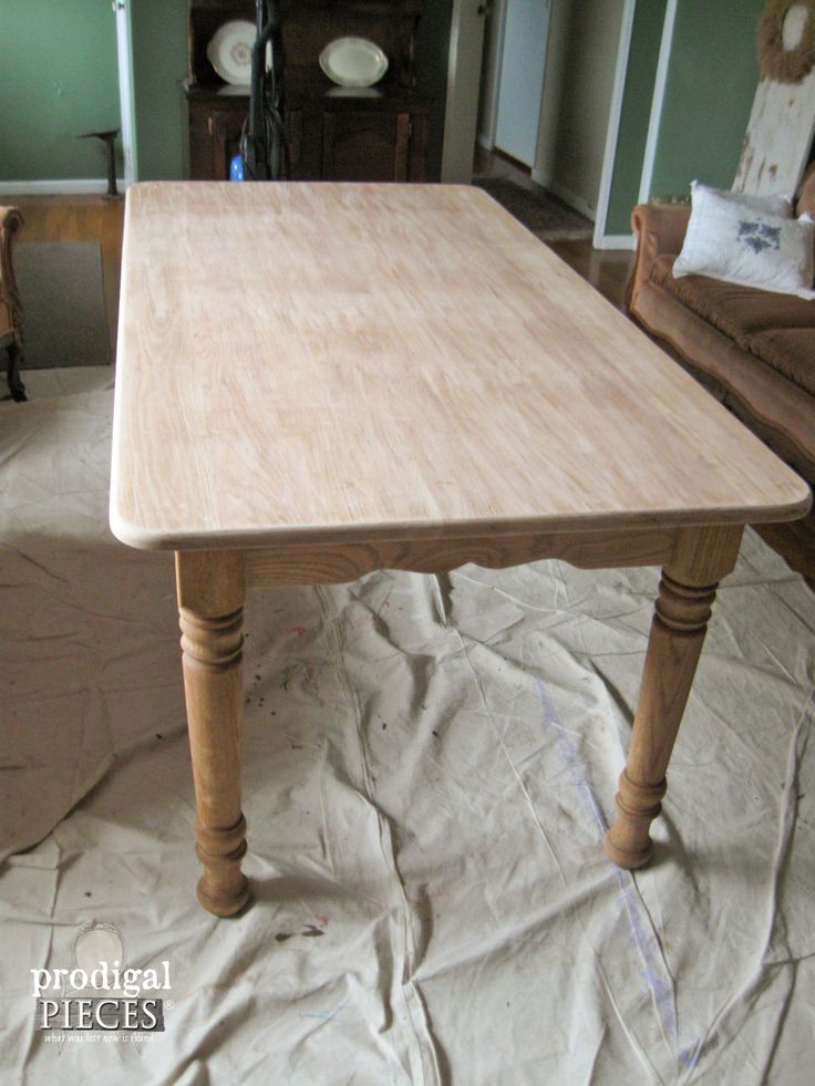 a wooden table sitting on top of a white sheeted floor next to two chairs