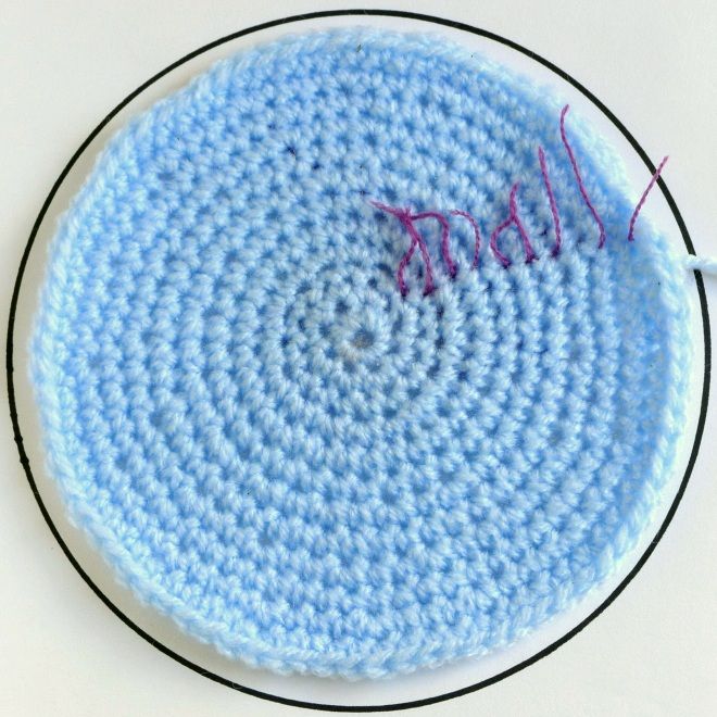 a blue crocheted dishcloth on a white table with a black trim around it