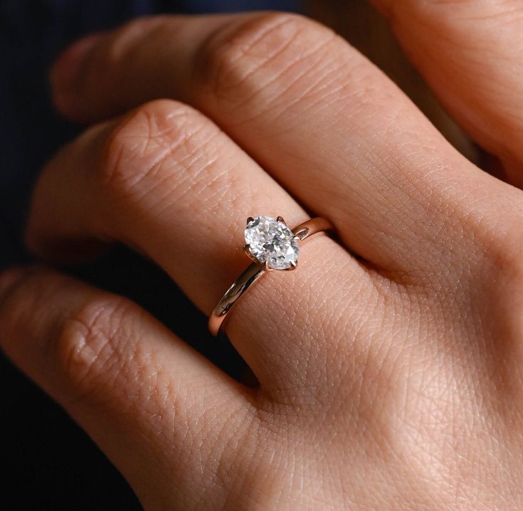 a woman's hand with a diamond ring on her left hand, showing the center stone