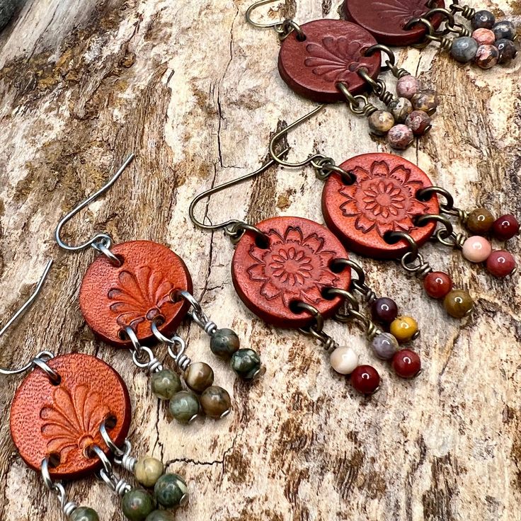 Leather coin earrings are cut from genuine veg tanned leather, stamped and dyed in a antiqued saddle tan or dark brown. Accented with a trio of natural stone dangles these rustic bohemian style compliments a variety of styles. 1.5" long total length on stainless steel or gold plated steel ear wires. Unique Brown Festival Earrings, Bohemian Brown Pierced Earrings, Earthy Brown Earrings For Festivals, Vintage Brown Earrings For Festivals, Artisan Stamped Brown Jewelry, Rust Bohemian Earrings For Pierced Ears, Earthy Brown Copper Earrings, Brown Leather Stamped Jewelry, Rustic Brown Hand-tooled Earrings