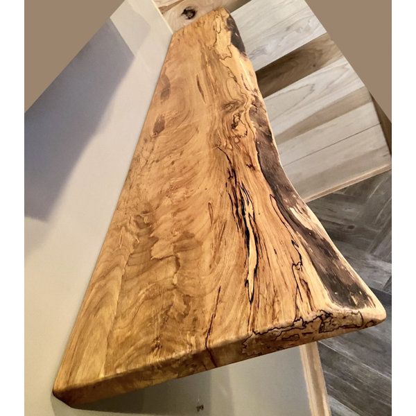 a piece of wood sitting on top of a wooden table next to a wall mounted clock