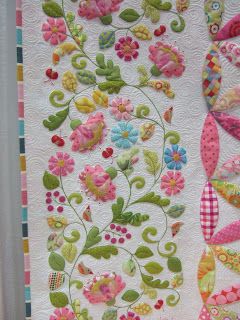 a quilted wall hanging with flowers and butterflies