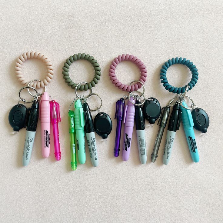 several different colored pens and key chains on a white surface