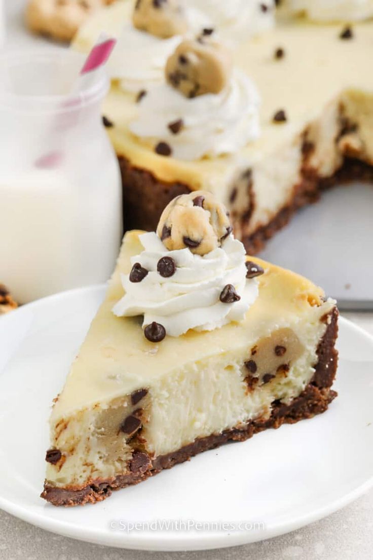 a slice of cheesecake with chocolate chips and whipped cream on top is sitting on a white plate