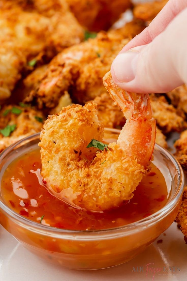 a person dipping some food into a small bowl with ketchup on the side