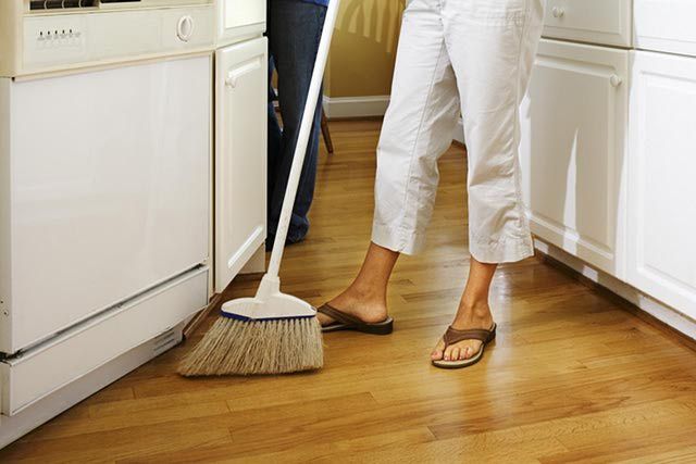 a woman is cleaning the floor with a mop in her hand while standing next to an oven