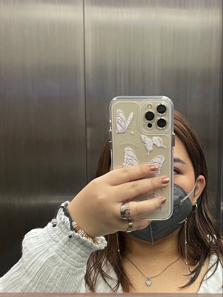 a woman taking a selfie with her cell phone in front of an elevator door