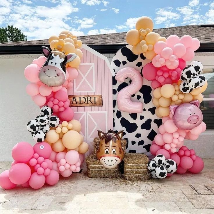 an animal themed birthday party with balloons and farm animals in front of a pink barn