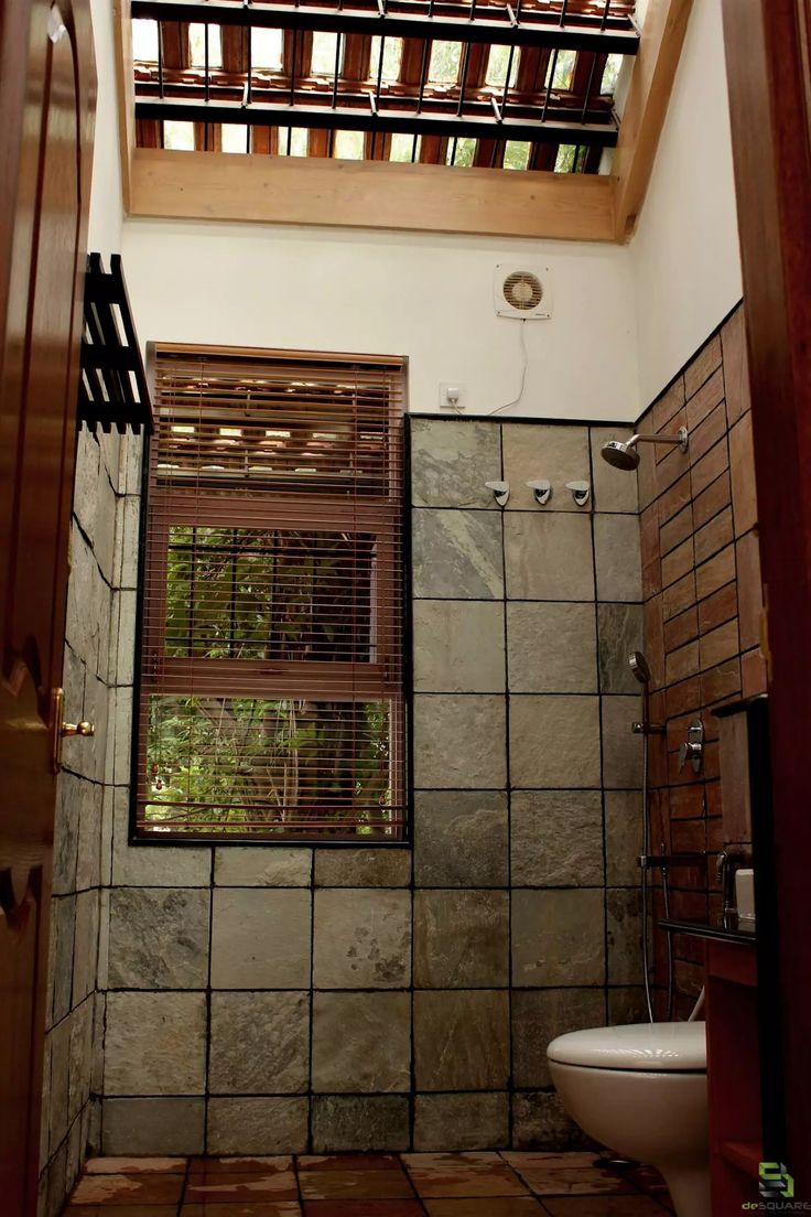 a bathroom with a toilet, window and tile flooring in the shower stall area