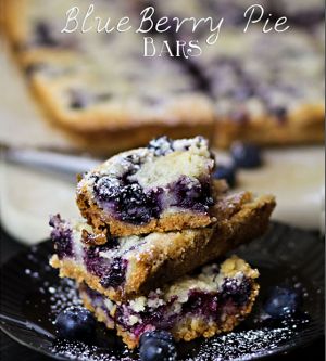 blueberry bars stacked on top of each other on a black plate with powdered sugar