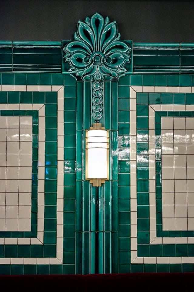 a green and white tiled wall with a lamp on it