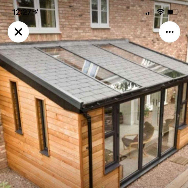 an image of a small wooden house with glass doors on the roof and side windows