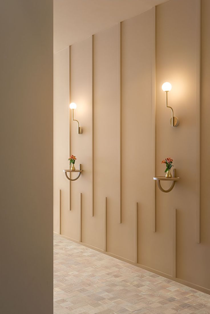 two lights are on the wall next to each other in a room with white walls and tile flooring