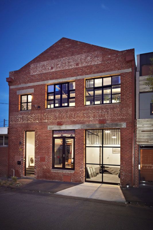 an old brick building is lit up at night with lights on the windows and doors