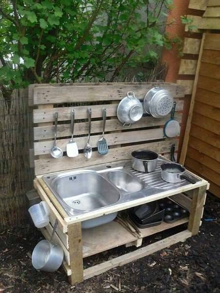 an outdoor kitchen made out of wooden pallets with pots and pans on it