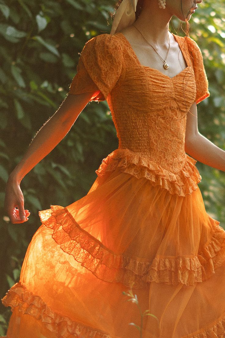 Step into a world of timeless tales and charm with the enchanting Raya dress. Its orange lace fabric and sweetheart neckline exude evermore, while the half length petal sleeves add a touch of whimsy. It features a maxi length skirt with a tiered tulle ruffle overlay. Orange Cottage Core Dress, Orange Dress With Sleeves, Orange Aesthetic Dress, Orange Dress Aesthetic, Raya Dress, Homecoming 2024, Petal Sleeves, Orange Bridesmaid, Orange Bridesmaid Dresses