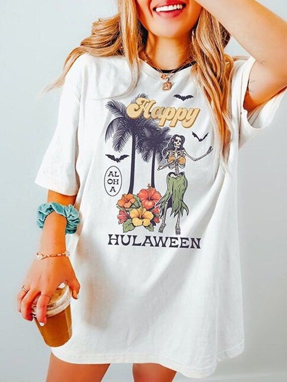 These hula dancing skeletons bring the spirit of Halloween to your wardrobe! Our designs are printed DTG (direct to garment) on high-quality Bella + Canvas brand tees. This soft Halloween tee is perfect for wearing on its own and easy to dress up with a cardigan. Made of 100% cotton for solid colors. Heather colors and sports grey include polyester. The collar is made with ribbed knitting to prevent curling damage. There are no itchy side seams on these t-shirts. Prefer this design on a Comfort Halloween Fun Skull Print T-shirt, White Top For Summer Costume Party, Fun Halloween Tops With Skull Print, Fun Halloween Skull Print Tops, Halloween Character Print Relaxed T-shirt, Fall Costume Party Short Sleeve T-shirt, Fall Short Sleeve T-shirt For Costume Party, Fall Short-sleeved T-shirt For Costume Party, Casual Graphic Print Top For Costume Party