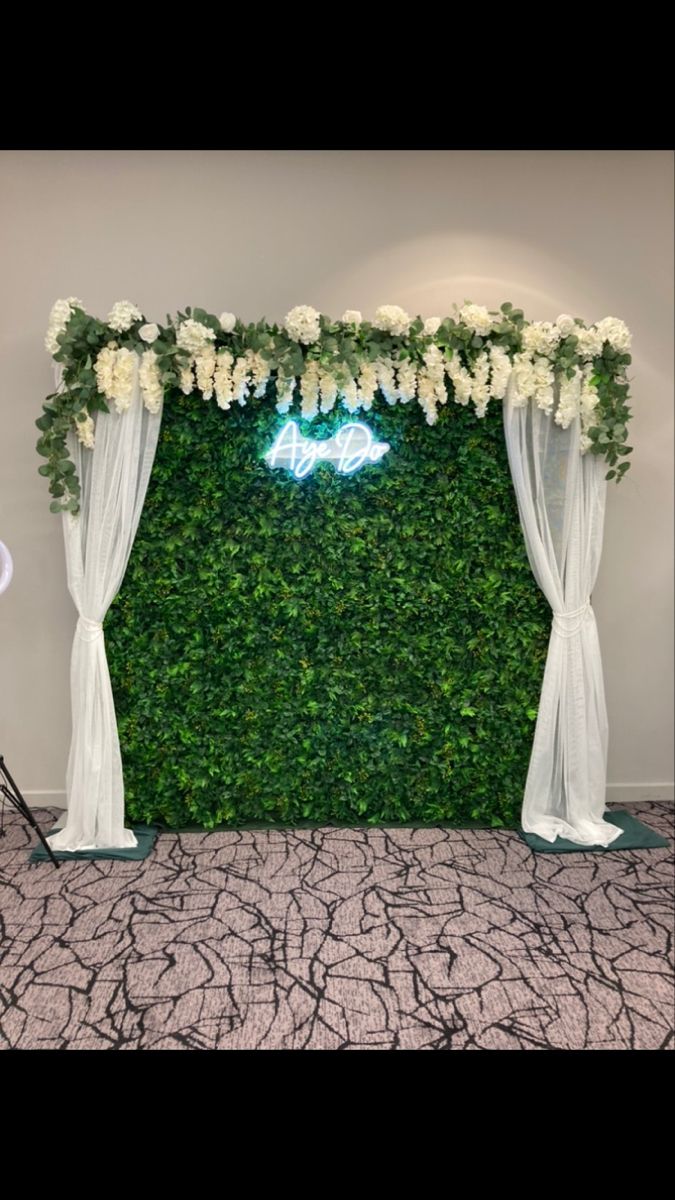 the backdrop is covered with white flowers and greenery for a wedding or special event