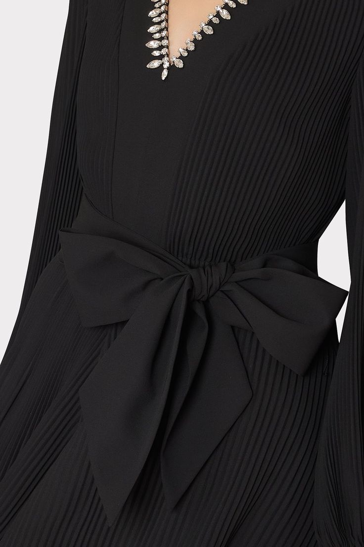 This black pleated mini dress features a slim peasant sleeve, a v-neckline, a pleated skirt, and a tie at the waist for added shape. It works so well for both day and night. This season’s take features a cocktail party-ready crystal embellished neckline. Peasant Sleeve, Embellished Neckline, Pleated Mini Dress, Maxi Dress Cocktail, Cocktail Evening Dresses, Swimsuit Cover Ups, Day And Night, Sweater And Shorts, Pleated Dress