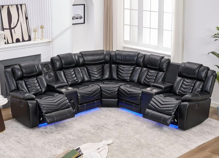 a living room filled with black leather couches and recliners in front of a fireplace