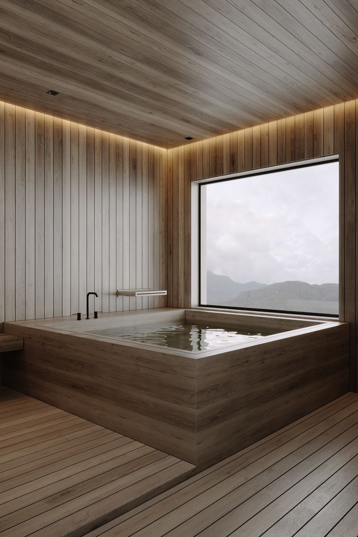 a large bath tub sitting in the middle of a wooden floored room next to a window