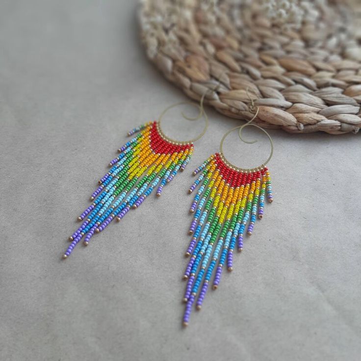 a pair of colorful beaded earrings sitting on top of a table next to a basket