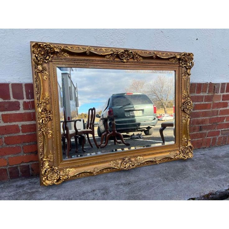 a large mirror reflecting the back of a van in front of a building with chairs