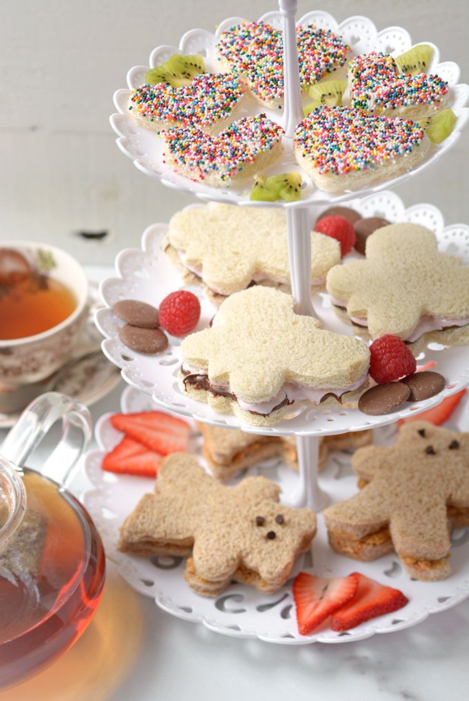 three tiered trays with cookies and pastries on them next to a cup of tea