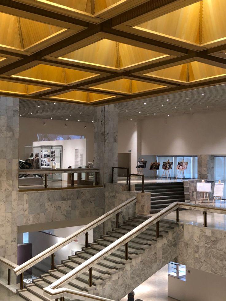 the interior of a modern building with marble stairs and railings leading up to an open floor plan