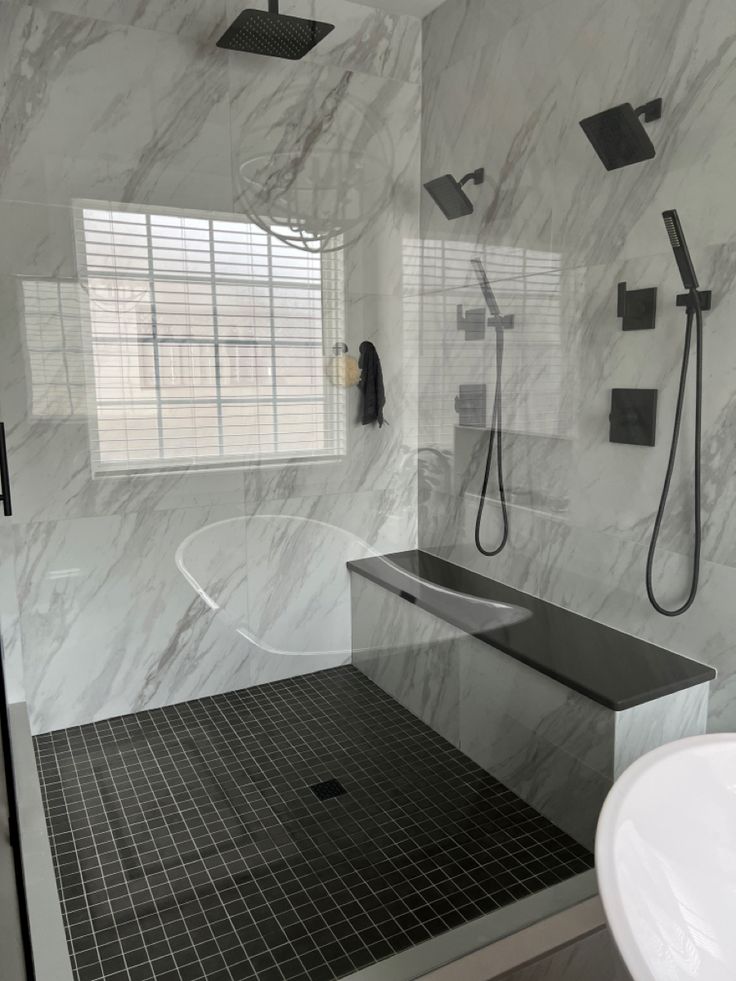 a bathroom with marble walls and black tile flooring