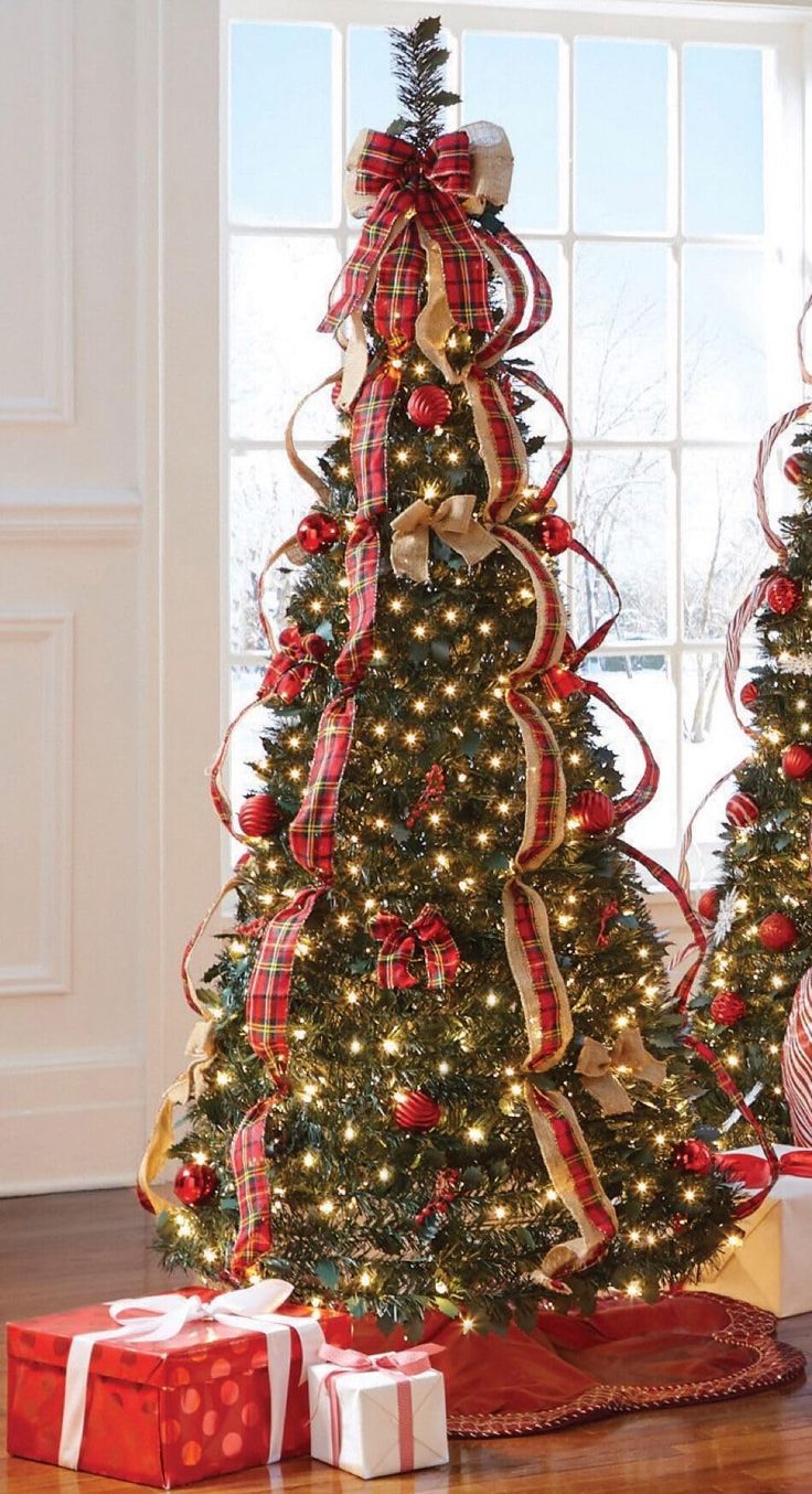 two christmas trees decorated with red, white and gold ribbons