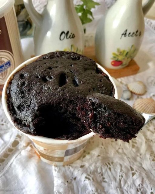 a chocolate cake in a bowl on a table next to milk bottles and spoons