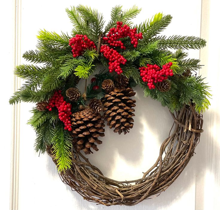 a wreath with pine cones and red berries