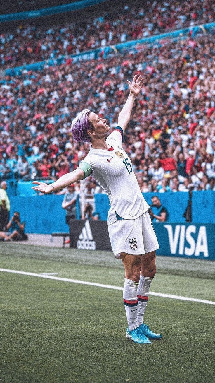 a man with purple hair is playing soccer in front of a large group of people