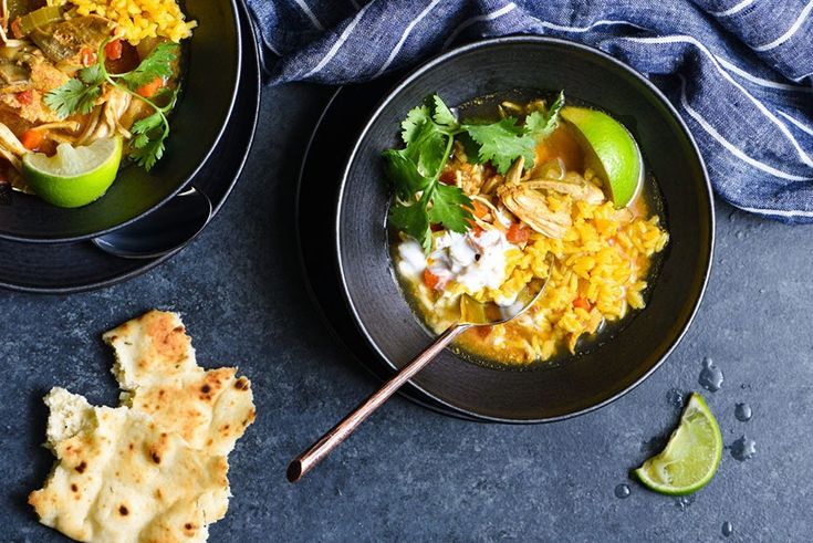 two black bowls filled with food and garnished with cilantro, lime wedges