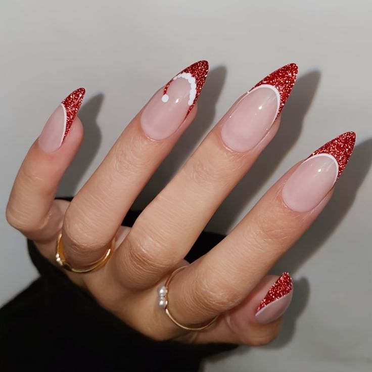 a woman's hand with red and white nail polish on her nails, wearing gold rings