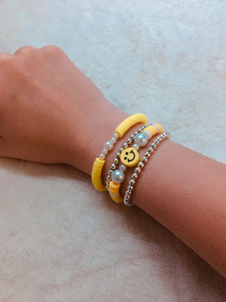 a person's arm with two bracelets and a smiley face charm on it